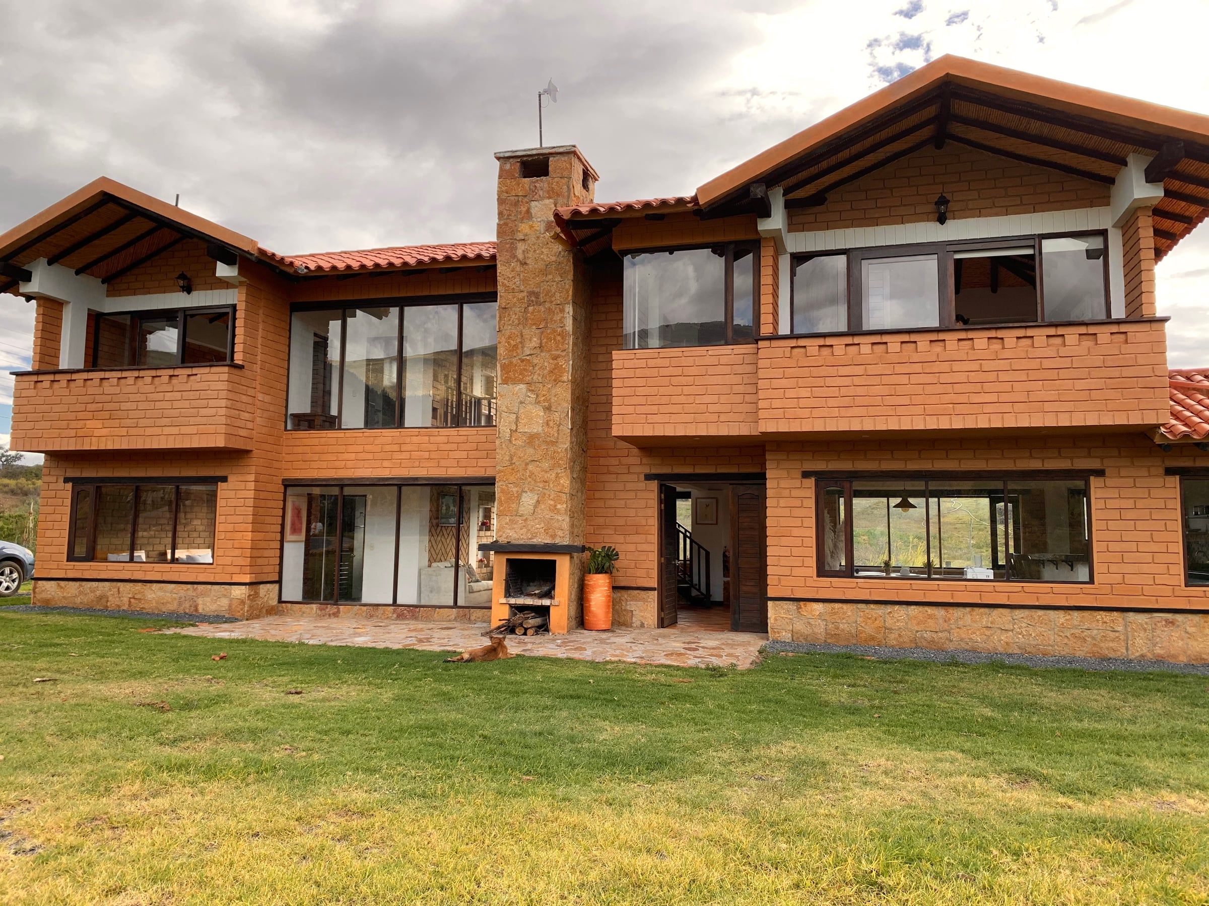 Fachada posterior de la Casa del Lago con dos balcones de madera, chimenea central y jardín