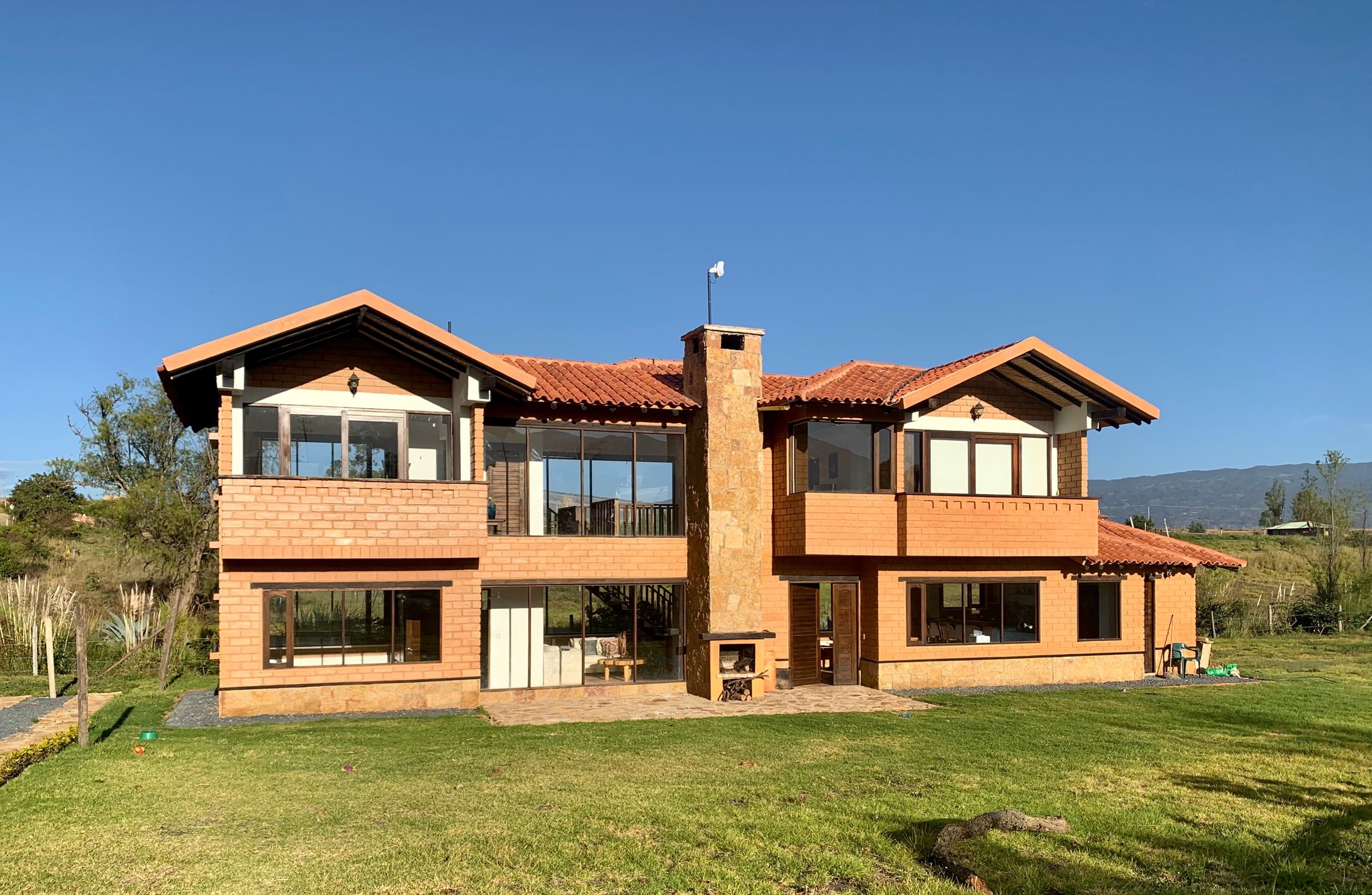Vista general de la Casa del Lago en su lote, con el cerro y el cielo de Villa de Leyva al fondo