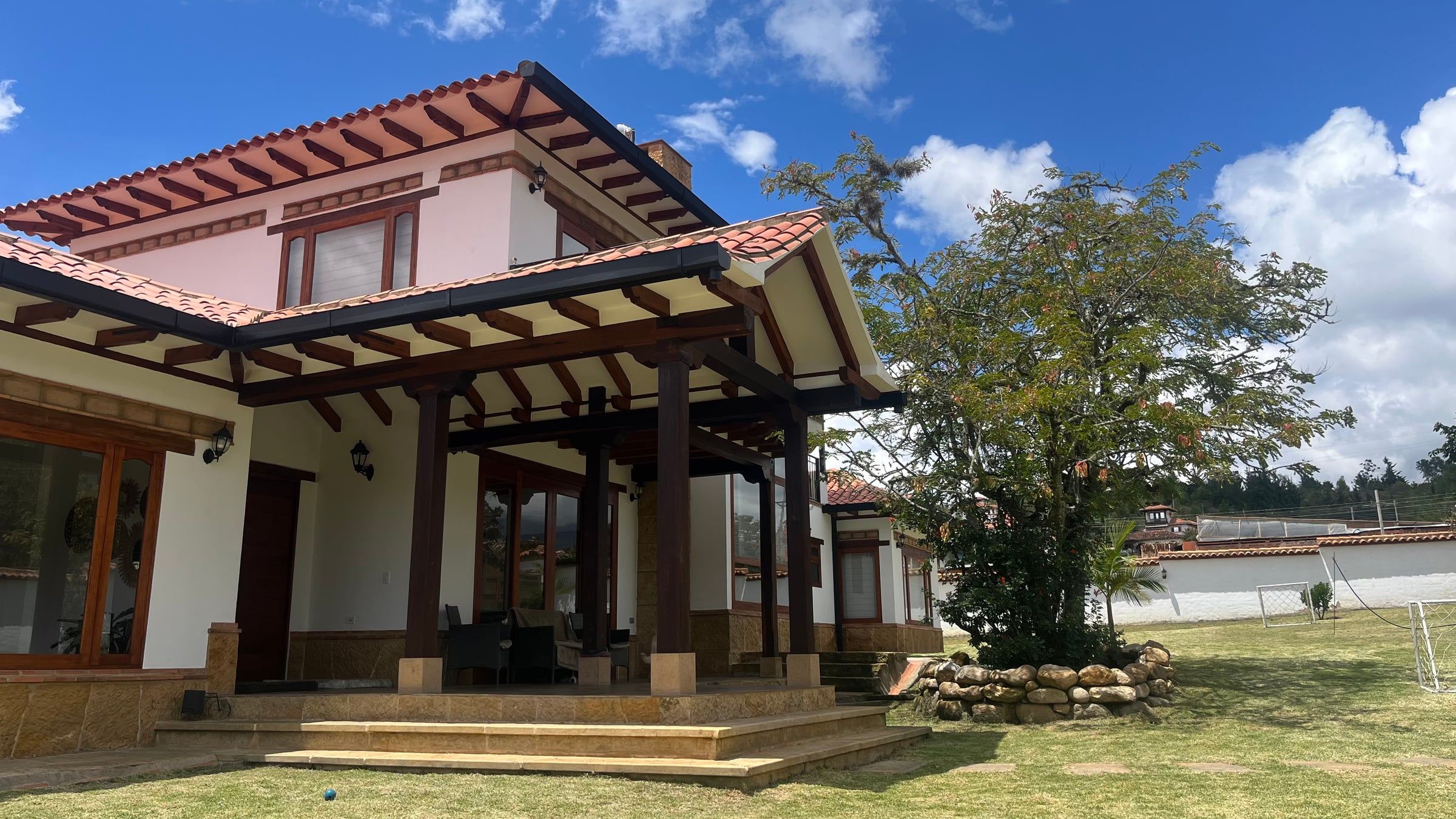 Fachada con corredor de columnas de madera y cubierta de teja en estilo colonial