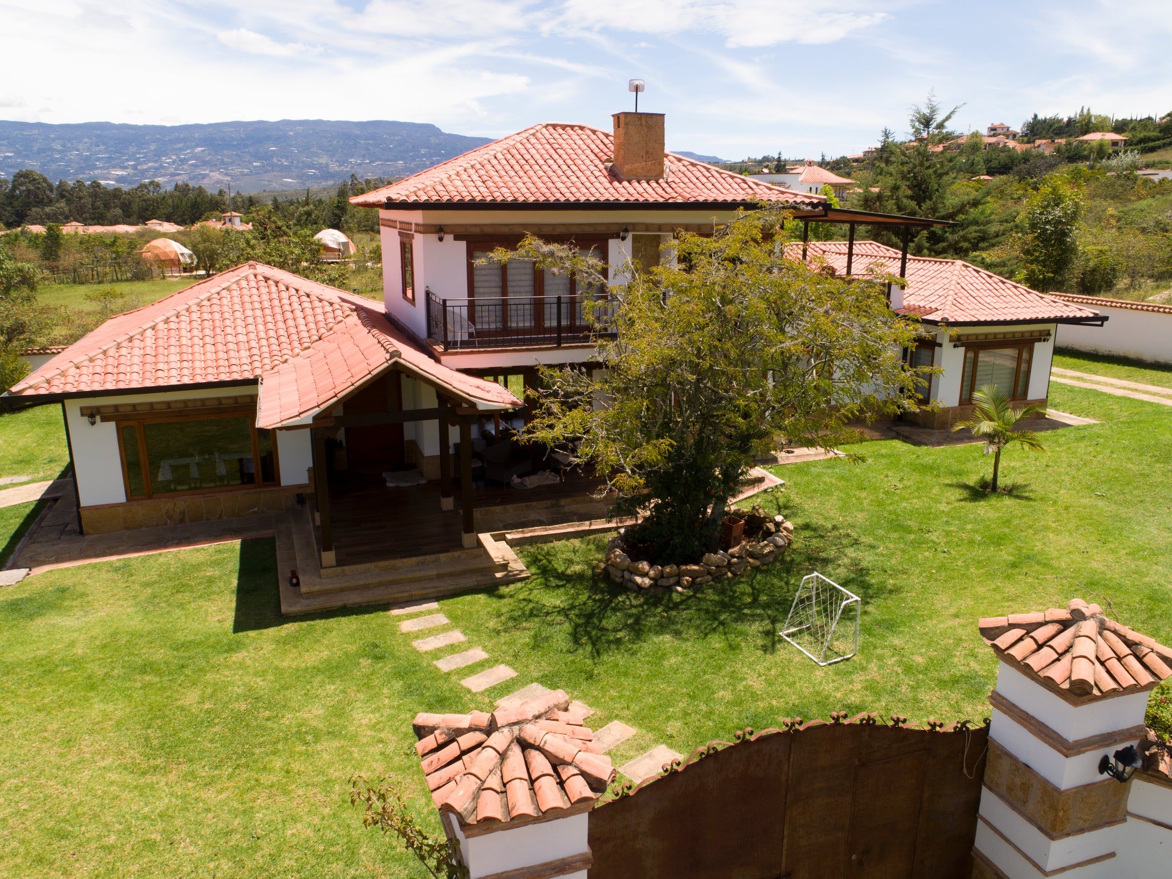 Vista aérea de la casa con el acceso, el jardín y los cerros del valle al fondo