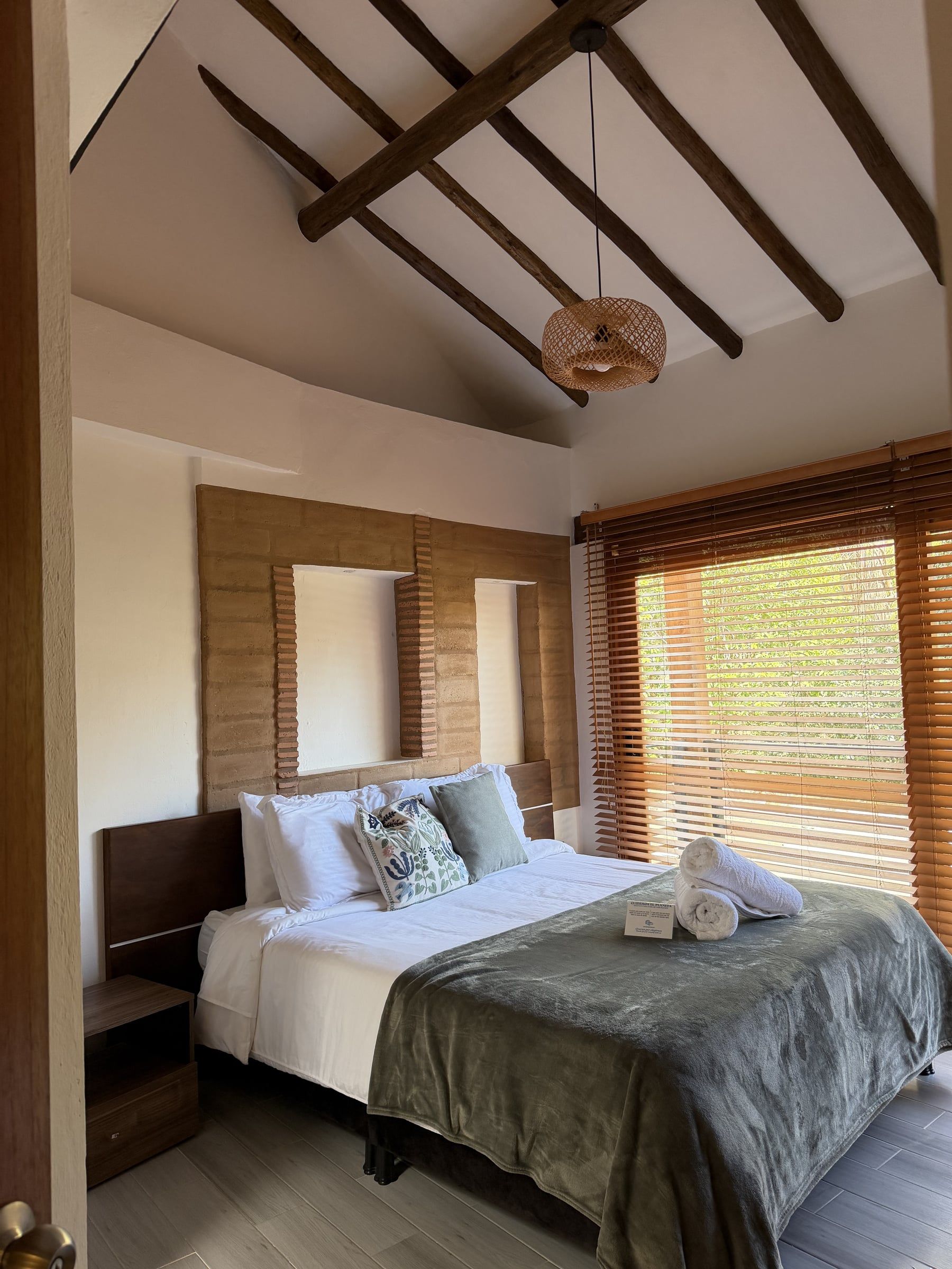 Habitación bajo cubierta de vigas de madera con muro de piedra y persianas de madera
