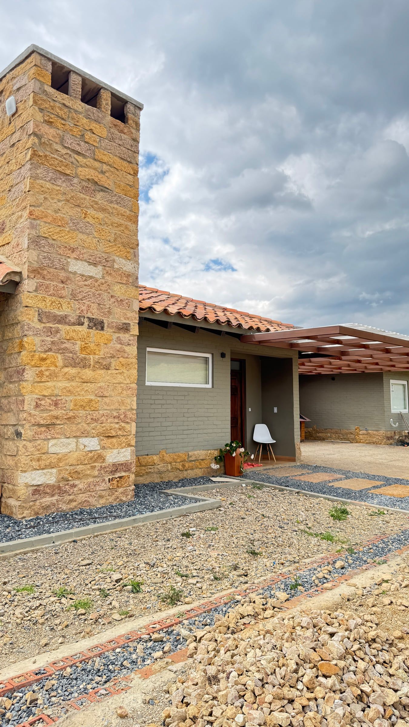 Volumen de la chimenea revestido en piedra junto a la cubierta de teja de barro
